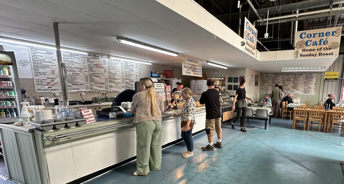 The Corner Café servery, with the full menu boards along the wall and Home of the Sunday Roast signs hanging above the counter